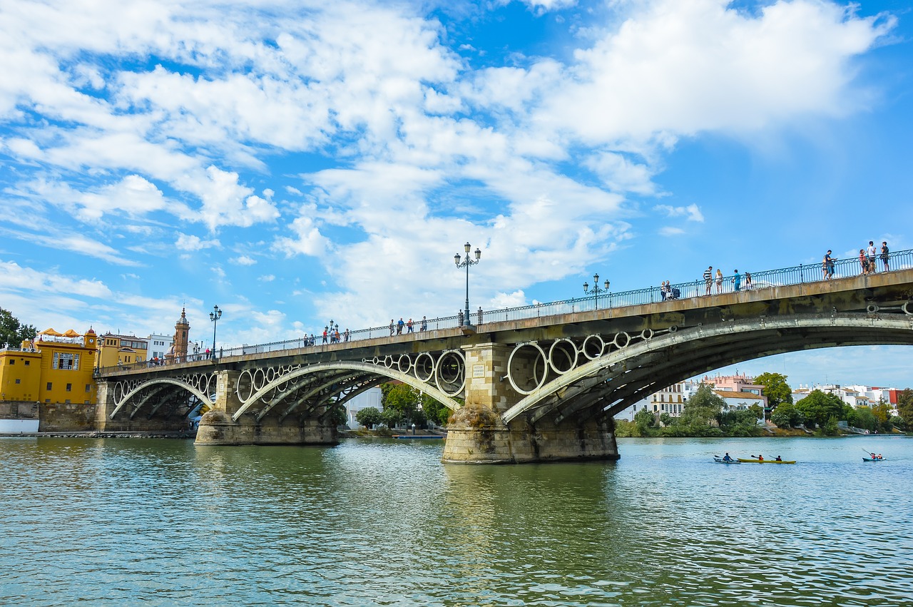 bridge,triana,seville,andalusia,spain,metal,city,water,river,guadalquivir,iron bridge,architecture,pedestrian,blue sky,engineering,sun,urban,canoes,free pictures, free photos, free images, royalty free, free illustrations, public domain