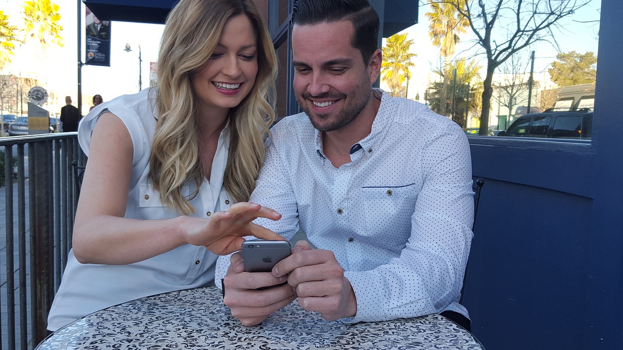 couple sitting holding phone free photo