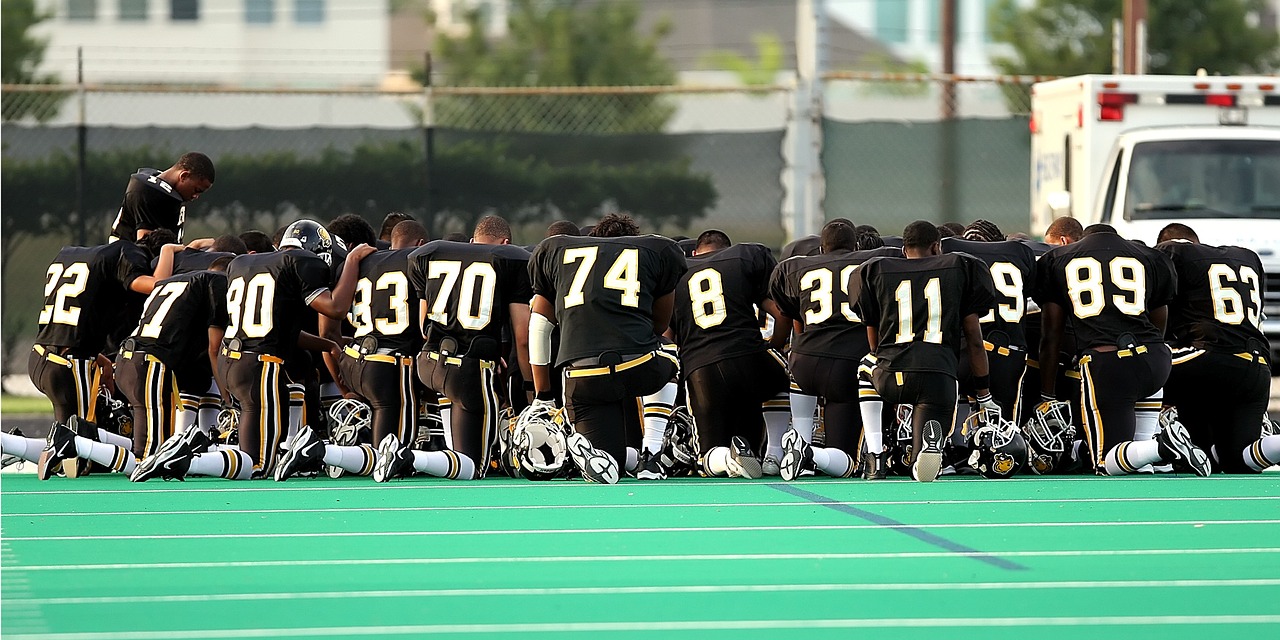 football team praying kneeling free photo