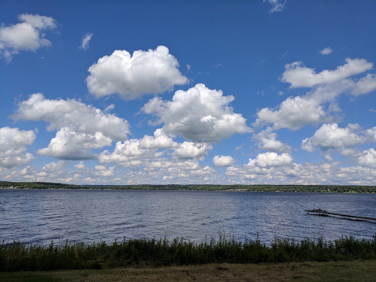 lake chautauqua fluffy clouds blue sky over water free photo