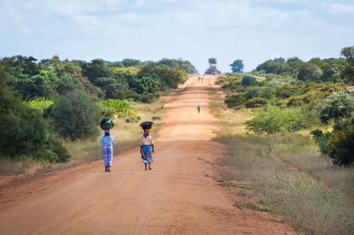 african women walking along road sand road to mapai african scene
