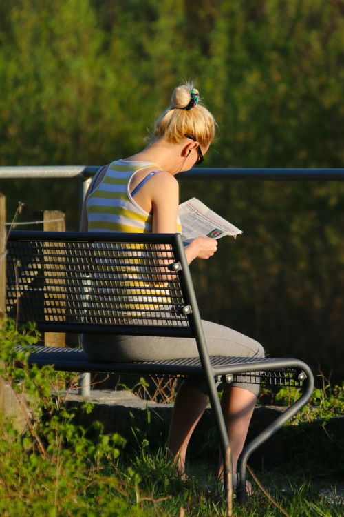 bench woman reading a newspaper