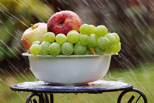 bowl of fruit in rain  grapes  apples