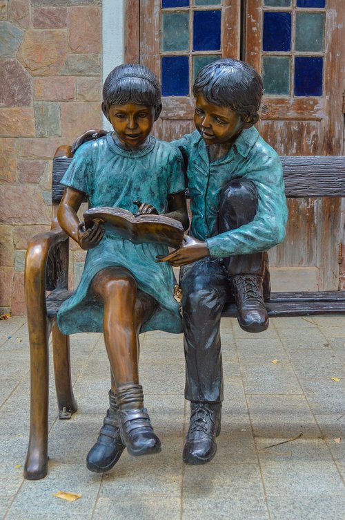 boy and girl reading  on the bench  nicely