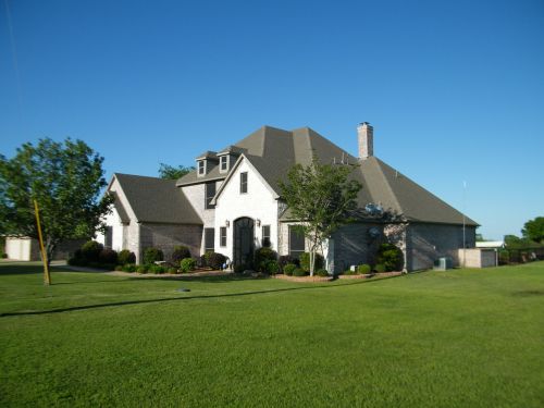 brick home blue sky green lawn