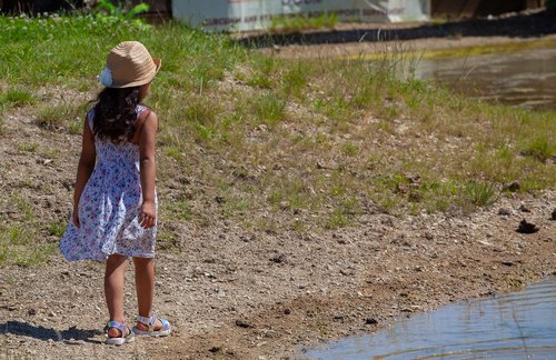 child on pond shore  child in hat  child