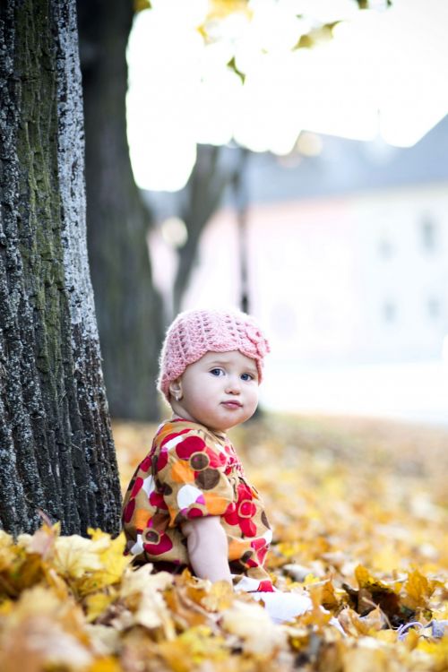 Child Sitting In Autumn Leaves