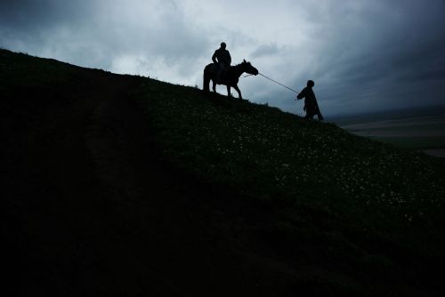 dark clouds horseback riding hillside