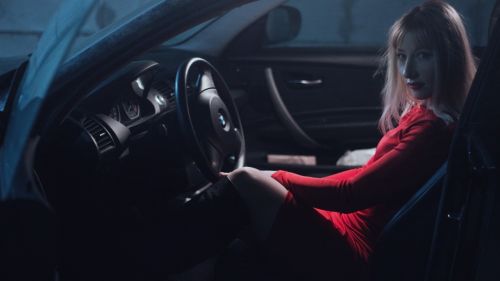 girl in car in a red dress behind the wheel