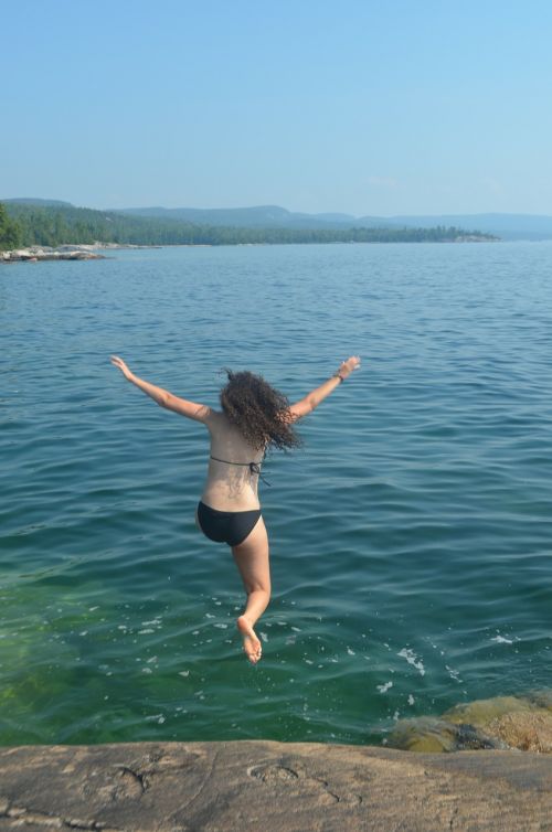 girl jumping into water swimming rock jump