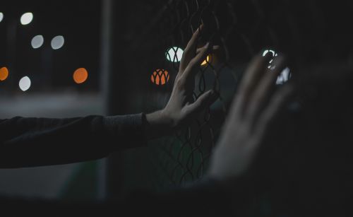 hands bokeh fence