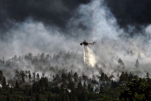 helicopter dropping water forest fire burning
