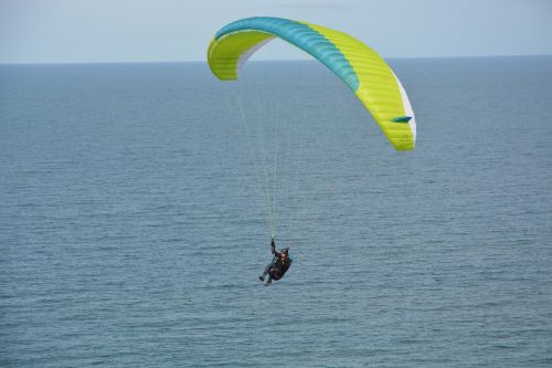paragliding flight over sea paraglider veil yellow green