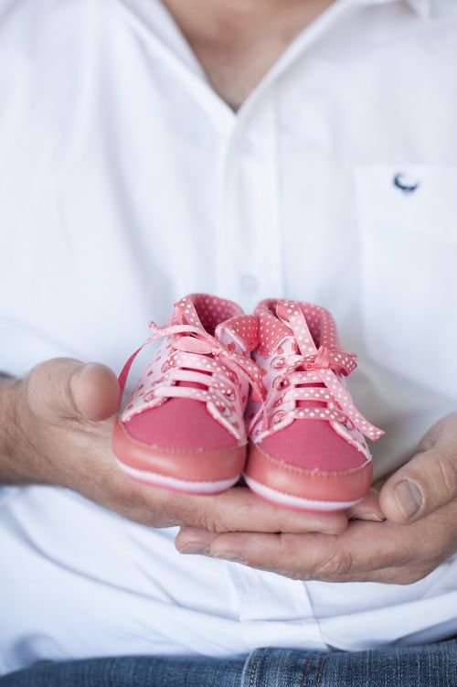 pink baby shoes father holding
