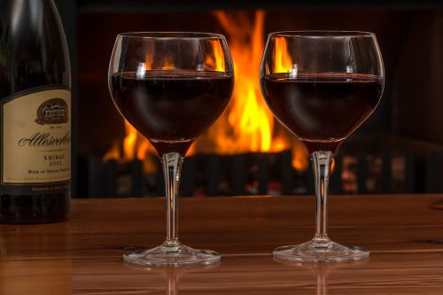 red wine glasses log fire