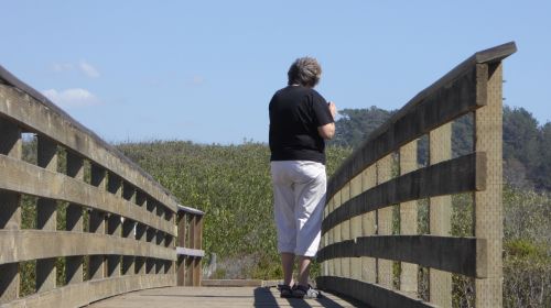 Senior Woman Walking Across Bridge