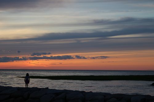 sunset over beach girl watching sunset over beach summer