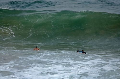 Surfers Rowing Towards Large Wave