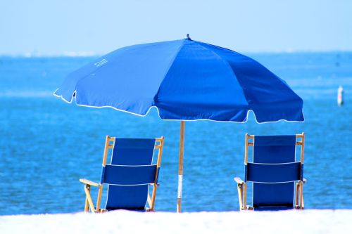 white sand blue water blue umbrella