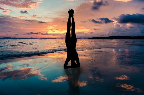 yoga stand in hands silhouette sunset beach zen position by the sea