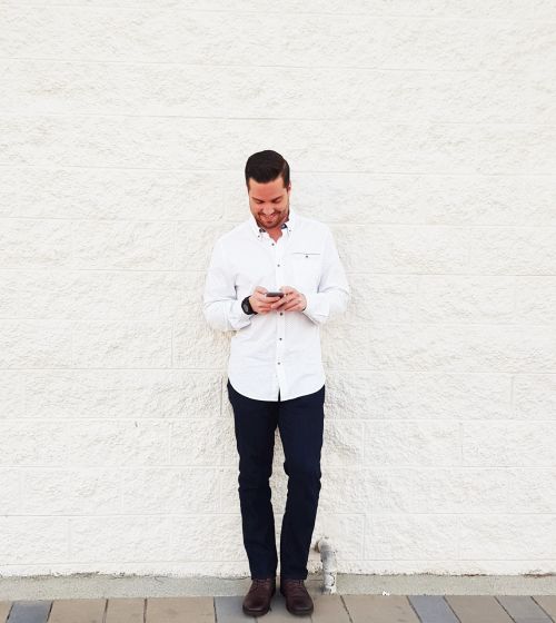 young man looking at phone brick wall